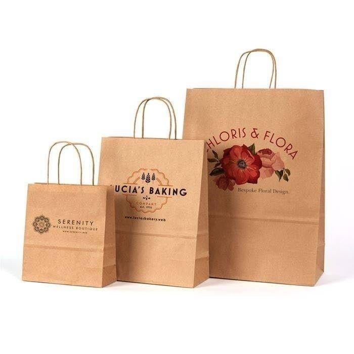 Three kraft paper shopping bags of decreasing size with business logos and branding for Serenity, Lucias Baking, and Gloris & Flora